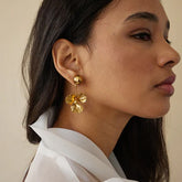 Model wearing Celene earrings styled with soft waves and vintage blouse
